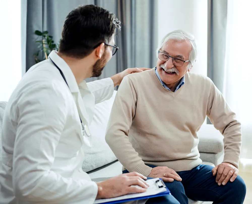 médico cardiovascular sentado con el paciente para hablar durante la visita en consulta